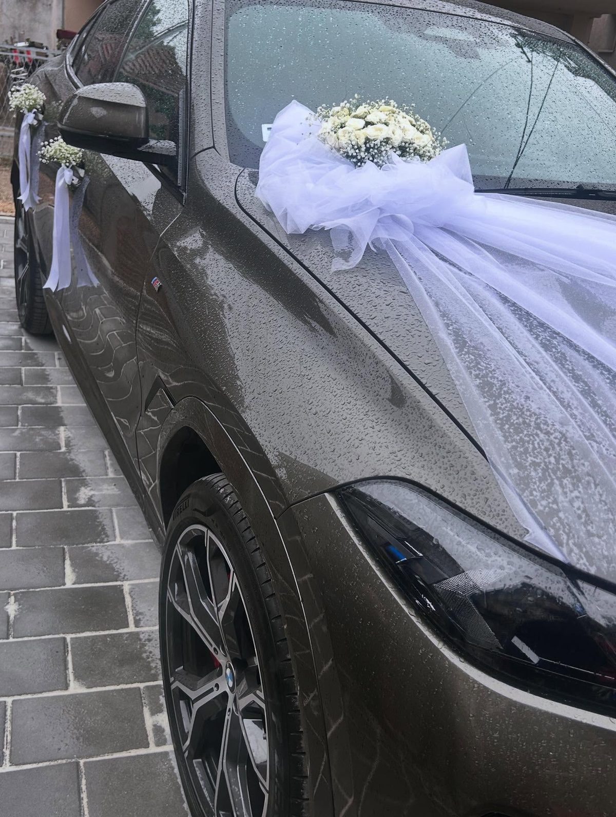 Dekoracija svadbenog automobila belim tilom i cvetnim aranžmanom