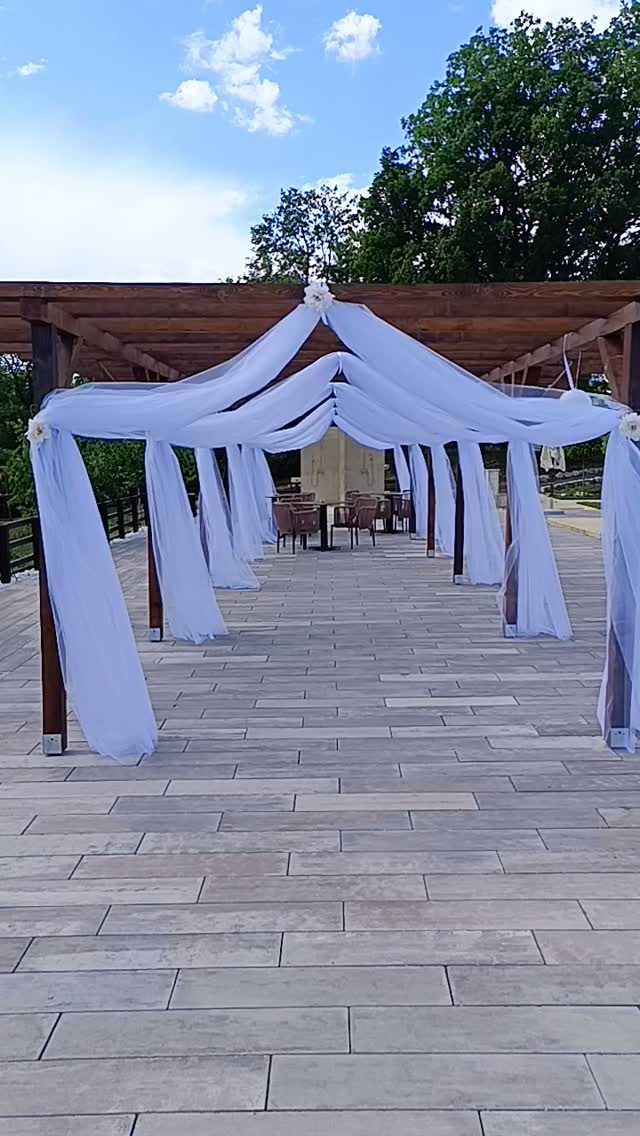 Pergola drapirana belim tilom kao prilaz svečanoj ceremoniji